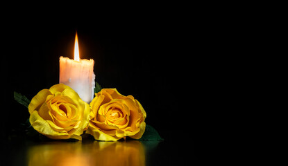 Fototapeta na wymiar LIGHTED CANDLE AND YELLOW ROSES ON DARK BACKGROUND. CONDOLENCE CARD FOR ALL SOULS DAY. COPY SPACE.