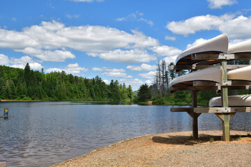 La Mauricie National Park Wapizagonke lake canoe rental station on a sunny day. Canoe on lake shore ready for paddling