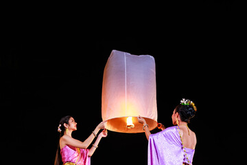 asian girl wearing thai dress playing with floating sky lantern at night,