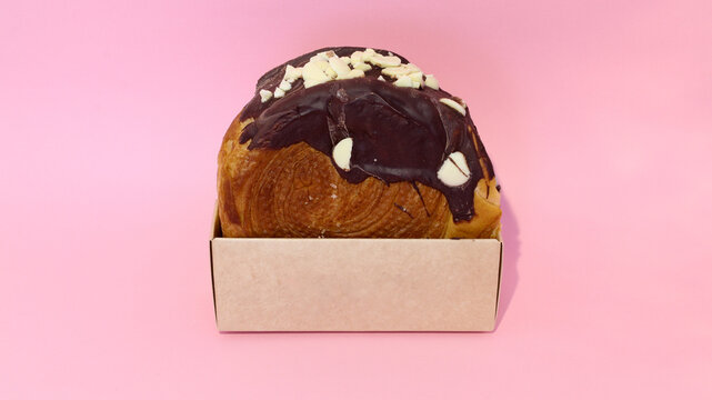 Roll con chocolate negro encima y chispas de chocolate blanco, con caja caf&eacute; sin marca y sin logotipos. 