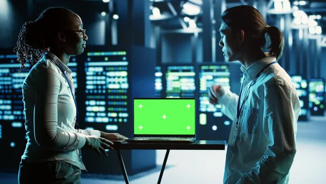 African american admin and colleague using mockup laptop to implement artificial intelligence parallel processing. Experts work on chroma key device enabling AI systems to do machine learning