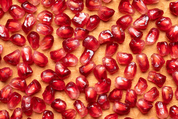 Pomegranate seeds background. Close-up of pomegranate seeds in wooden plate.