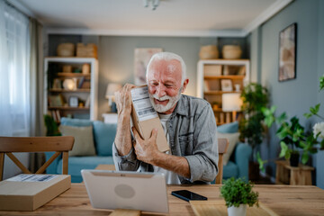 senior man sit at home hold post package delivery present or order