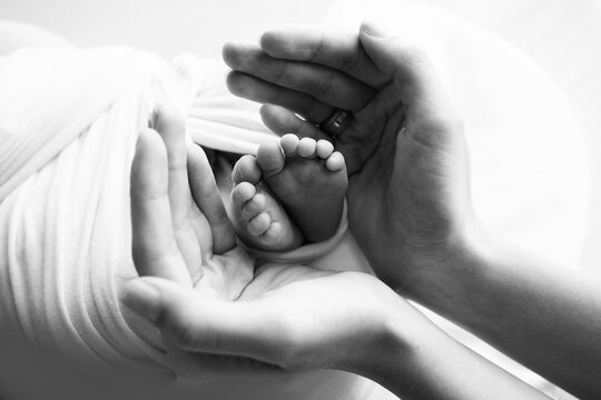 Little feet of a newborn in the hands of mom. The loving palm hand of a mother. 