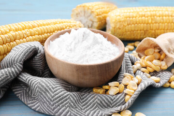 Bowl with corn starch, ripe cobs and kernels on light blue wooden table