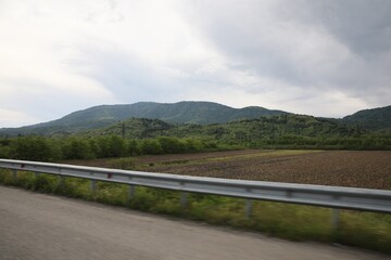 Picturesque view of asphalt road near mountains on cloudy day