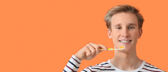 Young man with dental braces and tooth brush on orange background with space for text
