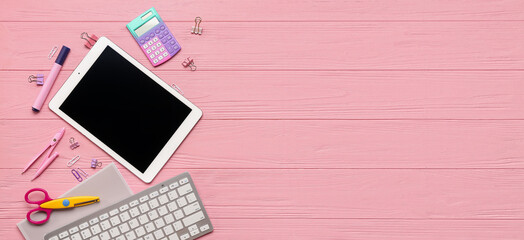 Tablet computer with keyboard and different stationery on pink wooden background with space for text