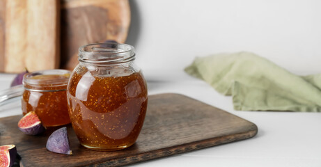 Jars of sweet fig jam on white table