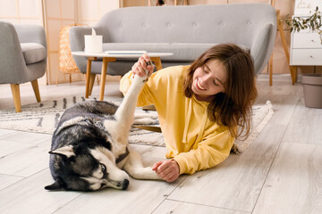 Happy young woman with husky dog at home