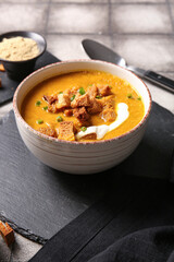 Bowl of tasty cream soup with croutons on grey tile background