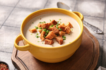 Pot of tasty cream soup with croutons on grey tile background