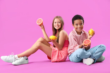 Little children with fresh grapefruits and lemons sitting on purple background