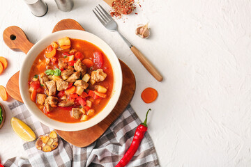 Bowl of tasty beef stew and ingredients on white background