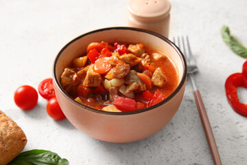 Bowl of tasty beef stew on light background
