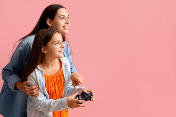 Happy mother and her little daughter with game pad on pink background - obrazy, fototapety, plakaty