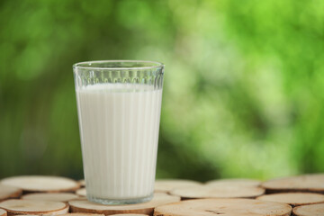 Glass of fresh milk on wooden table outdoors