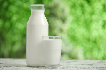 Glass and bottle of fresh milk on grunge table outdoors