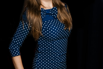 Female skinny figure brunette with long hair in a blue tight-fitting dress with a polka dot pattern...
