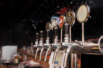 A line of taps of draft beer in the bar of the establishment, close-up