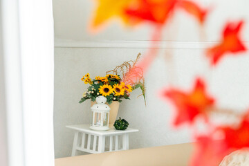 Autumn composition with a bouquet, a lantern and pumpkin in the interior of a bright living room