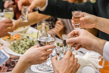 The hands of a group of people clink glasses and glasses of alcohol at a feast in a restaurant