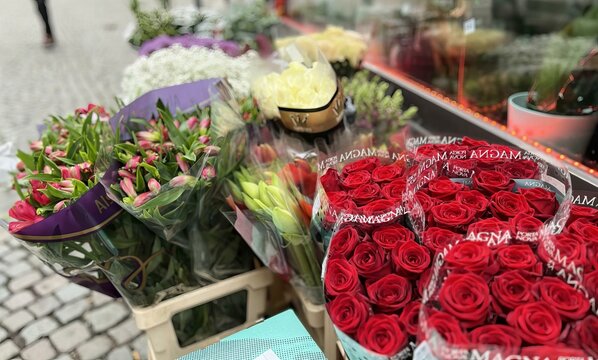 a photography of a bunch of flowers on a table outside, grocery store display of red roses and other flowers for sale.