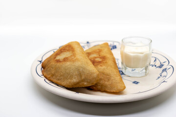 Front view fried empanadas filled with meat, with garlic sauce. Traditional food in Venezuela. White background, selective focus.