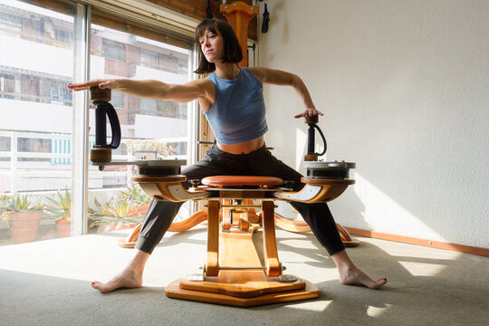 front view of woman stretching and working shoulders and arms with exercise machine at home