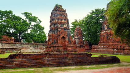 Fototapeta na wymiar Touristen in Ayutthaya besichtigen die schönen alten Stupas entlang Weg mit grüner Wiese