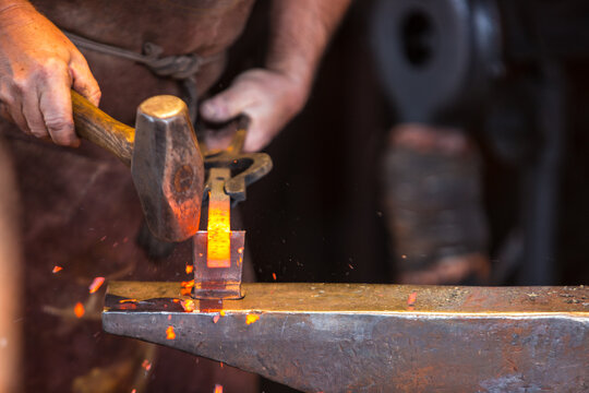 Blacksmith forging metal with tools