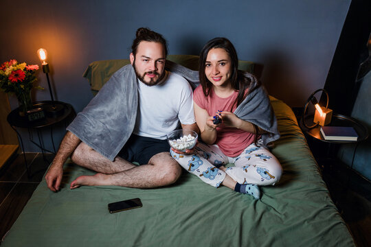 latin couple watching movie in laptop on bed at home at night in Mexico Latin America, hispanic people having fun