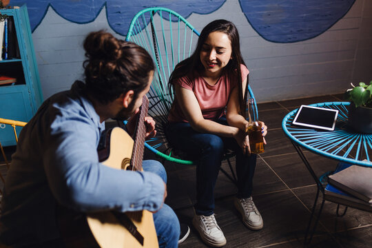 young latin couple playing guitar in a romantic date, Girlfriend and boyfriend singing in home at night in Mexico Latin America, hispanic people