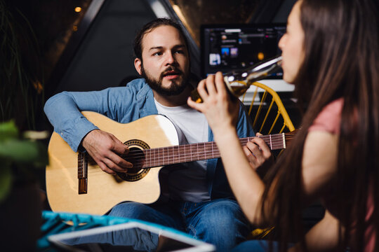 young latin couple playing guitar in a romantic date, Girlfriend and boyfriend singing in home at night in Mexico Latin America, hispanic people