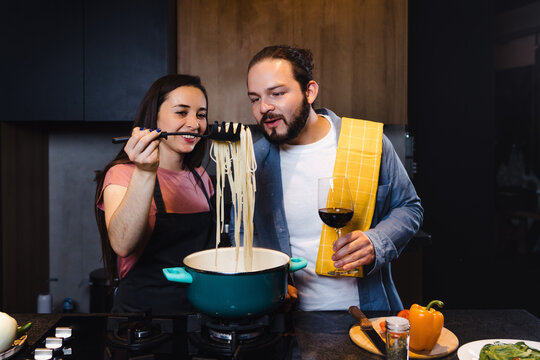 Young latin couple cooking dinner together in kitchen in home at night in Mexico Latin America, hispanic people in love