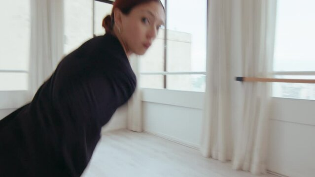 Young stylish girl posing on camera and performing graceful dance moves and turns, dancing contemporary style in a studio. Zoom shot, handheld camera