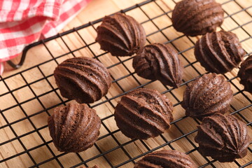 chocolate choux on a cooling rack. Sweet pastry is made from wheat flour, eggs, chocolate, sugar. blurred image.