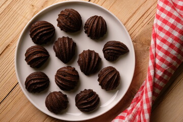 chocolate choux on a round white plate. Sweet pastry is made from wheat flour, eggs, chocolate, sugar. blurred image