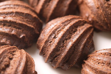 chocolate choux on a white plate. Sweet pastry is made from wheat flour, eggs, chocolate, sugar. blurred image.