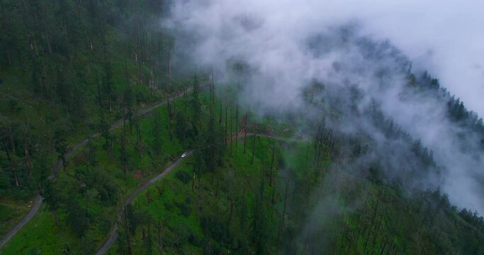Forward-moving drone shot of Forest fog Nepal, White clouds, 4x4 Jeep travel the hill slope. Adventurous Nepali tourism with astounding nature. 4K