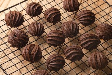chocolate choux on a cooling rack. Sweet pastry is made from wheat flour, eggs, chocolate, sugar. blurred image.