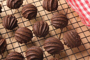 chocolate choux on a cooling rack. Sweet pastry is made from wheat flour, eggs, chocolate, sugar. blurred image. sus coklat.  - obrazy, fototapety, plakaty