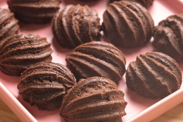 chocolate choux on a pink plate. Sweet pastry is made from wheat flour, eggs, chocolate, sugar. blurred image.