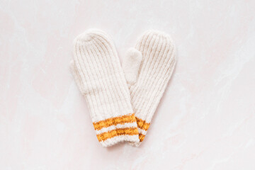 A flatlay of two cream and mustard mittens in the shape of a hea