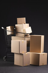 Vertical image of shopping trolley with boxes and copy space over black background