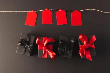 Foto op Aluminium Red gift tags on pegs and black gift boxes with copy space over black background © vectorfusionart