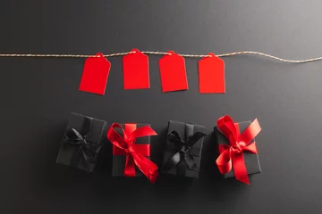 Foto op Canvas Red gift tags on pegs and black gift boxes with copy space over black background © vectorfusionart