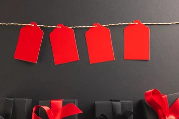  Red gift tags on pegs and black gift boxes with copy space over black background © vectorfusionart