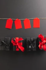 Deurstickers Vertical image of red gift tags on pegs and black gift boxes with copy space over black background © vectorfusionart