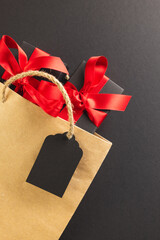 Vertical image of gift boxes with ribbon, gift bag with copy space over black background